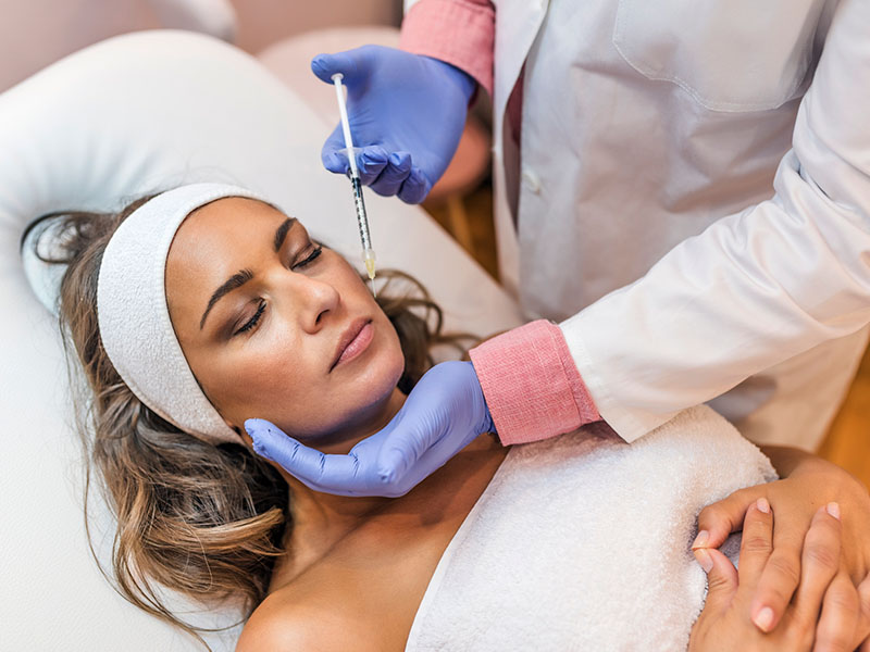 Woman resting in exam chair preparing to receive Botox from a dentist.
